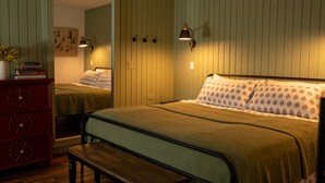 A bedroom with a bed, a dresser, a bench, and wall-mounted lamps. - Beautiful Apartment in Hawaii (Captain Cook)