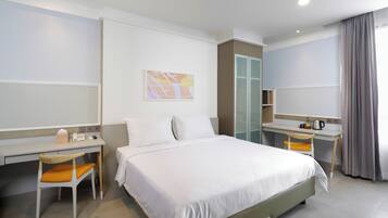 A hotel room with a bed, a desk, a chair, a wardrobe, and a bathroom.