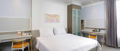 A hotel room with a bed, a desk, a chair, a wardrobe, and a bathroom.