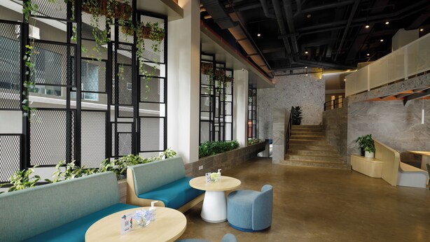 A modern interior with seating areas, tables, and a staircase. - Joylive BSD City (Pagedangan)