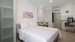 A modern hotel room with a large bed, a bedside table, a mirror, and an air conditioning unit. - Joylive BSD City (Pagedangan)