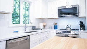 A modern kitchen with white cabinetry, a stainless steel range, and a built-in microwave.