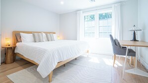 A bedroom with a bed, bedside table, lamp, and a window with curtains.