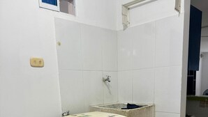 Une petite salle de bain compacte, avec des carreaux blancs, un lavabo et un lave-linge.