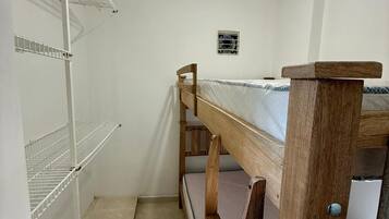 A bunk bed room with white walls, a ceiling light, and a small air conditioning unit.