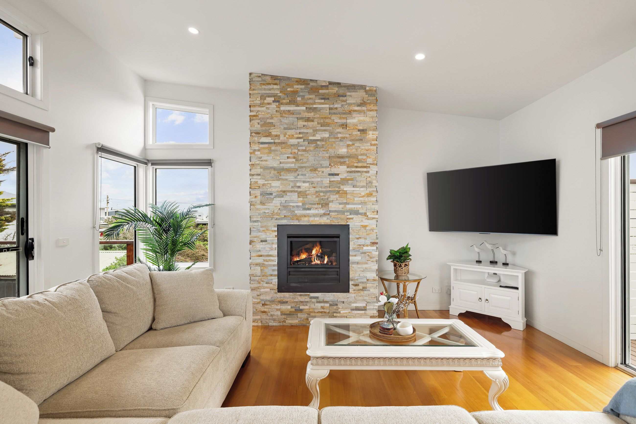 A modern living room with a stone fireplace, a flat-screen TV, and a comfortable sofa.