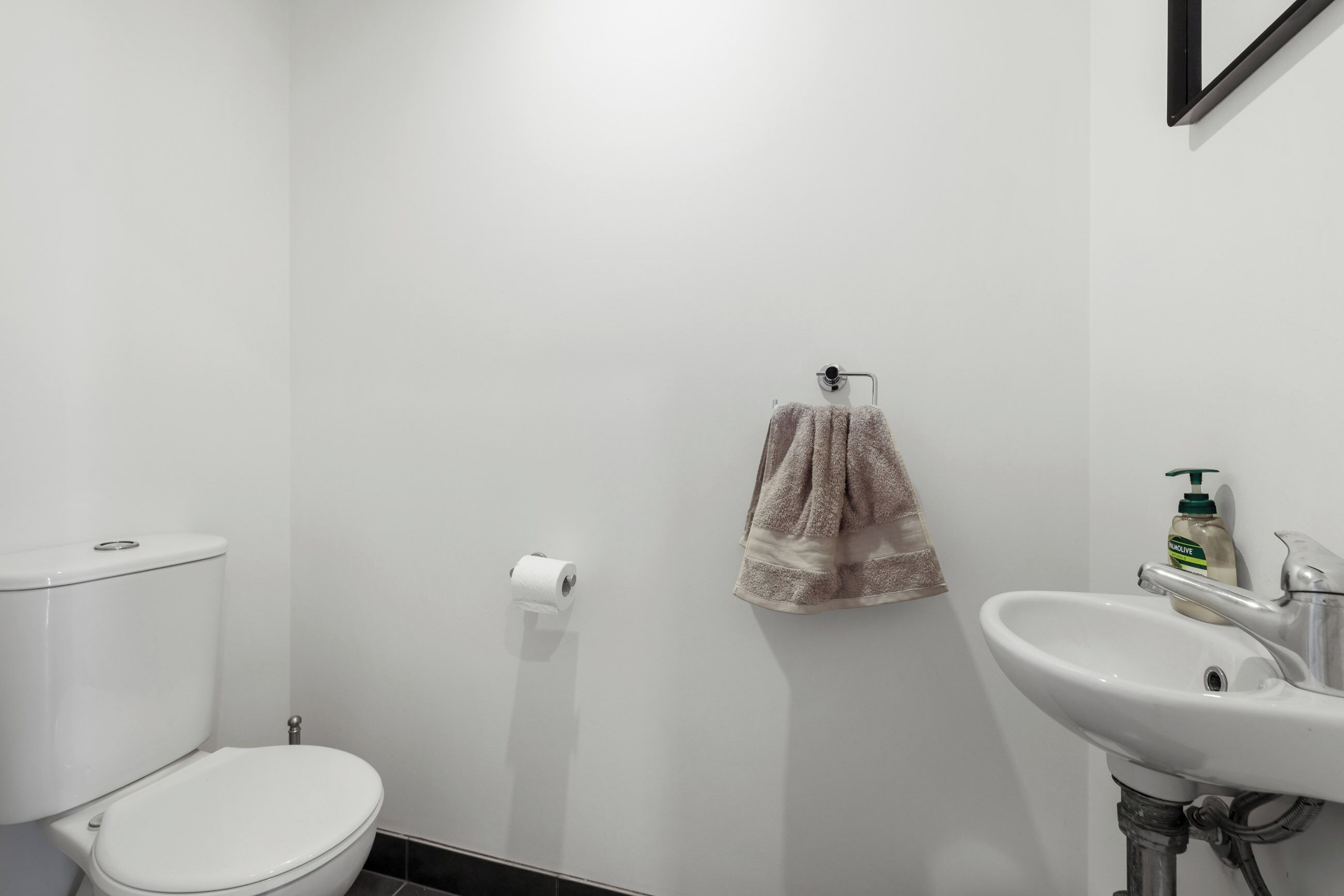A bathroom with a toilet, a sink, and a towel hanging on the wall.