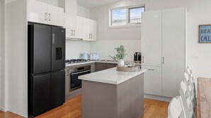 Une cuisine moderne avec des meubles blancs, un réfrigérateur noir et un îlot central.