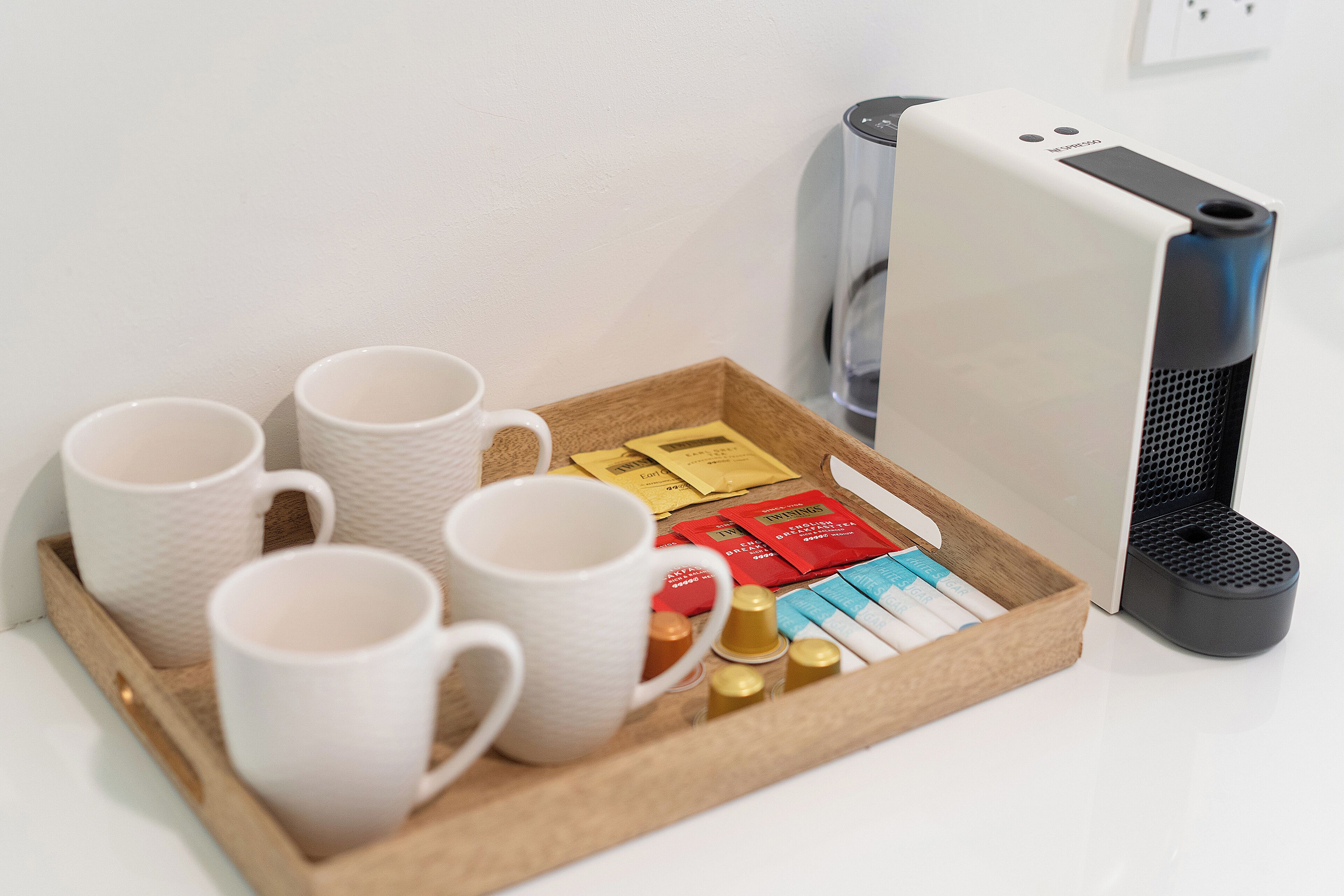 A tray with white mugs, a coffee maker, and various coffee pods.