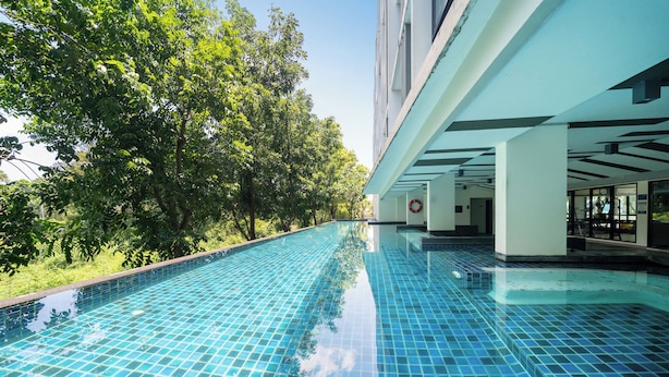 A swimming pool with a tiled floor and a view of a building with a balcony. - Zcape X2 Condominium in Bang Tao (Choeng Thale)