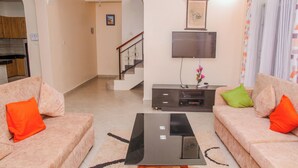 A living room with two sofas, a coffee table, a TV on a stand, and a staircase leading to another level. - Lovely Villa in Kilifi with Stunning Views (Kilifi)