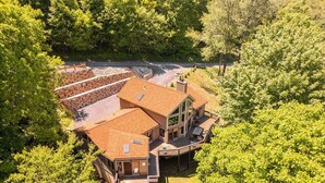 Ein großes, zweistöckiges Haus mit rotem Dach, umgeben von dichtem Grün.