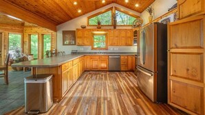 Eine geräumige Küche mit Holzausstattung, einem Edelstahlkühlschrank und einem großen Fenster.