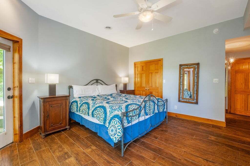 Ein Schlafzimmer mit einem Bett, Nachttischen aus Holz, einem Deckenventilator und einer Tür.