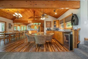 Eine geräumige Küche mit Holzausstattung, eine Essecke mit Korbstühlen und ein Deckenventilator.