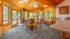 Ein Holzinterieur mit Essbereich, großen Fenstern und einer Decke mit Oberlichtern.