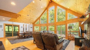 Un salón espacioso con un gran ventanal, una chimenea y un sillón de cuero reclinable.