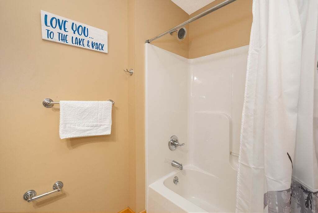 Un baño con bañera, perchero, cortina de ducha y un cartel en la pared.