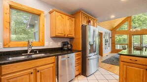 Una cocina con armarios de madera, electrodomésticos de acero inoxidable y ventanas amplias.