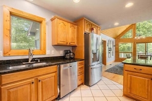 A kitchen with wooden cabinets, stainless steel appliances, and large windows.