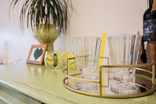 A bar area with a green bar counter, a bottle of wine, and three glasses on a tray.