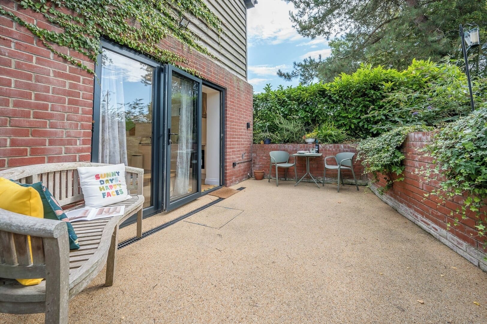 Une terrasse avec un banc en bois, une table et des chaises.