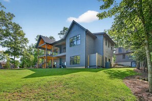 A modern two-story house with a covered patio and a well-maintained lawn. - Dockside of the Moon | Lakefront Luxury, Views & Private Dock (Nebo)
