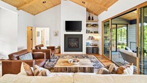 A modern living room with a fireplace, wooden ceiling, and large sliding glass doors to a balcony.