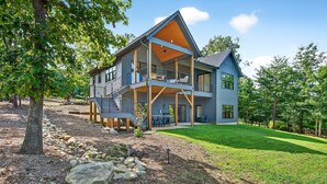 A two-story house with a balcony, a covered patio, and a well-maintained lawn.