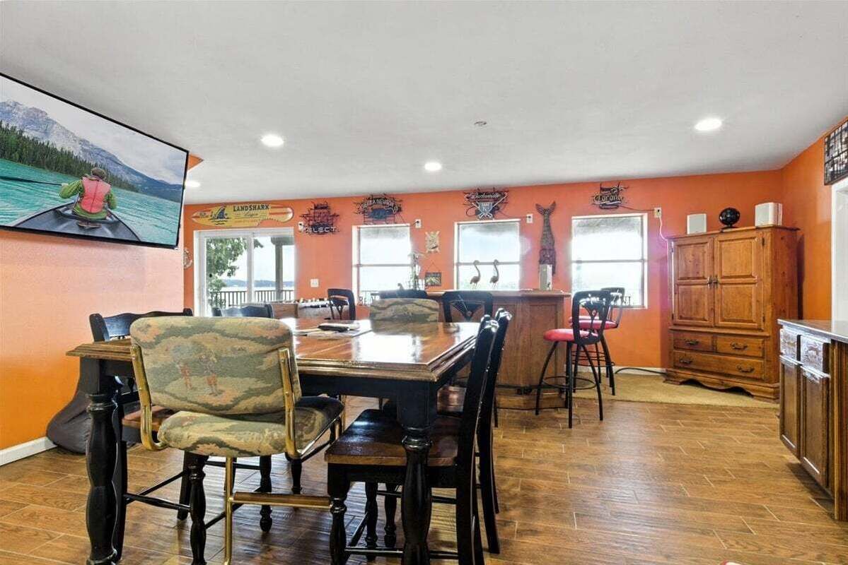 A dining area with a wooden table and chairs, a kitchen counter, and a large window.