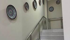 A staircase with a metal handrail and a wall with decorative plates.