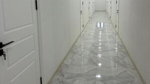 A hallway with white doors and a marble floor.