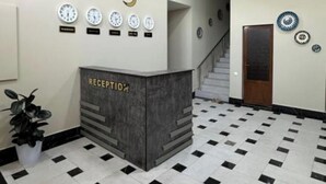 A reception area with a checkered floor, a reception desk labeled "RECEPTION," and several wall clocks.
