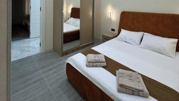 A bedroom with a large bed, a wooden headboard, and a mirror.