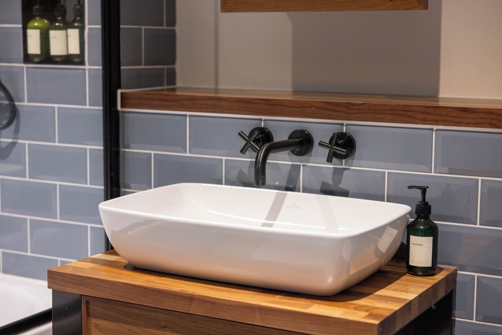 A bathroom with a white rectangular sink, wooden countertop, and a mirror above it.