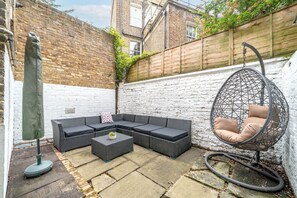 A patio with a sectional sofa, a round hanging chair, and a small table.