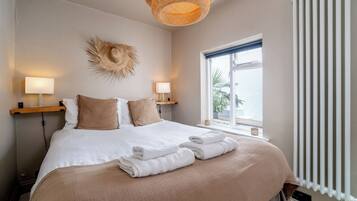 A hotel room with a bed, bedside lamps, a window with a view, and a radiator.