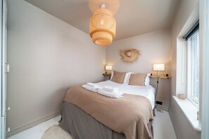 Un dormitorio con cama, lámparas de noche, un adorno en la pared y una ventana.