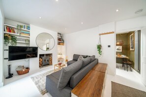 Un salon moderne comprenant un canapé, un téléviseur à écran plat, une cheminée et un coin repas.