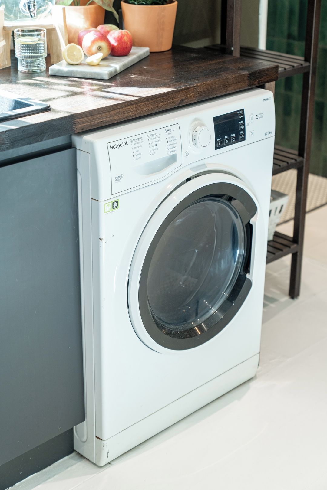 A front-loading washing machine with a digital control panel, placed on a kitchen counter.