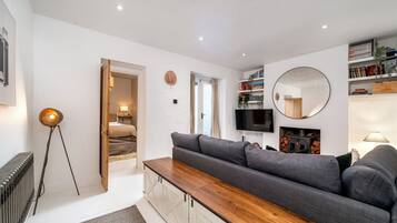 A modern living room with a sofa, a coffee table, a TV, and a fireplace.