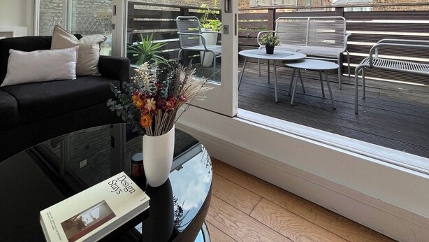 Un salon moderne doté d’une grande porte-fenêtre coulissante donnant sur un espace patio extérieur.