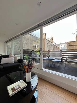 Un salon moderne doté d’une grande porte-fenêtre coulissante donnant sur un espace patio extérieur.