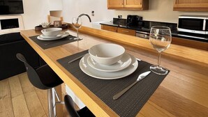 Une cuisine moderne avec des meubles en bois, un îlot central aménagé en coin repas et une lucarne au-dessus.