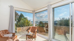 A spacious balcony with a seating area, large windows, and a view of greenery and buildings. - Greenbank, Holiday Property Dale, Sleeps 6, 3 bedrooms,  bathrooms (Haverfordwest)