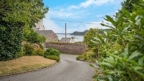 A narrow road flanked by lush greenery and stone walls, leading to a coastal area with boats visible in the distance. - Greenbank, Holiday Property Dale, Sleeps 6, 3 bedrooms,  bathrooms (Haverfordwest)