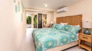 A bedroom with a patterned bedspread, a wooden headboard, and a nightstand with a lamp. - Villa Casabella | Ocean View - Located in  Fabulous Saint James with Private Pool (Saint James)