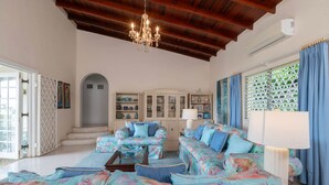 A spacious living room with a high ceiling, a chandelier, and a view of the outside. - Villa Casabella | Ocean View - Located in  Fabulous Saint James with Private Pool (Saint James)