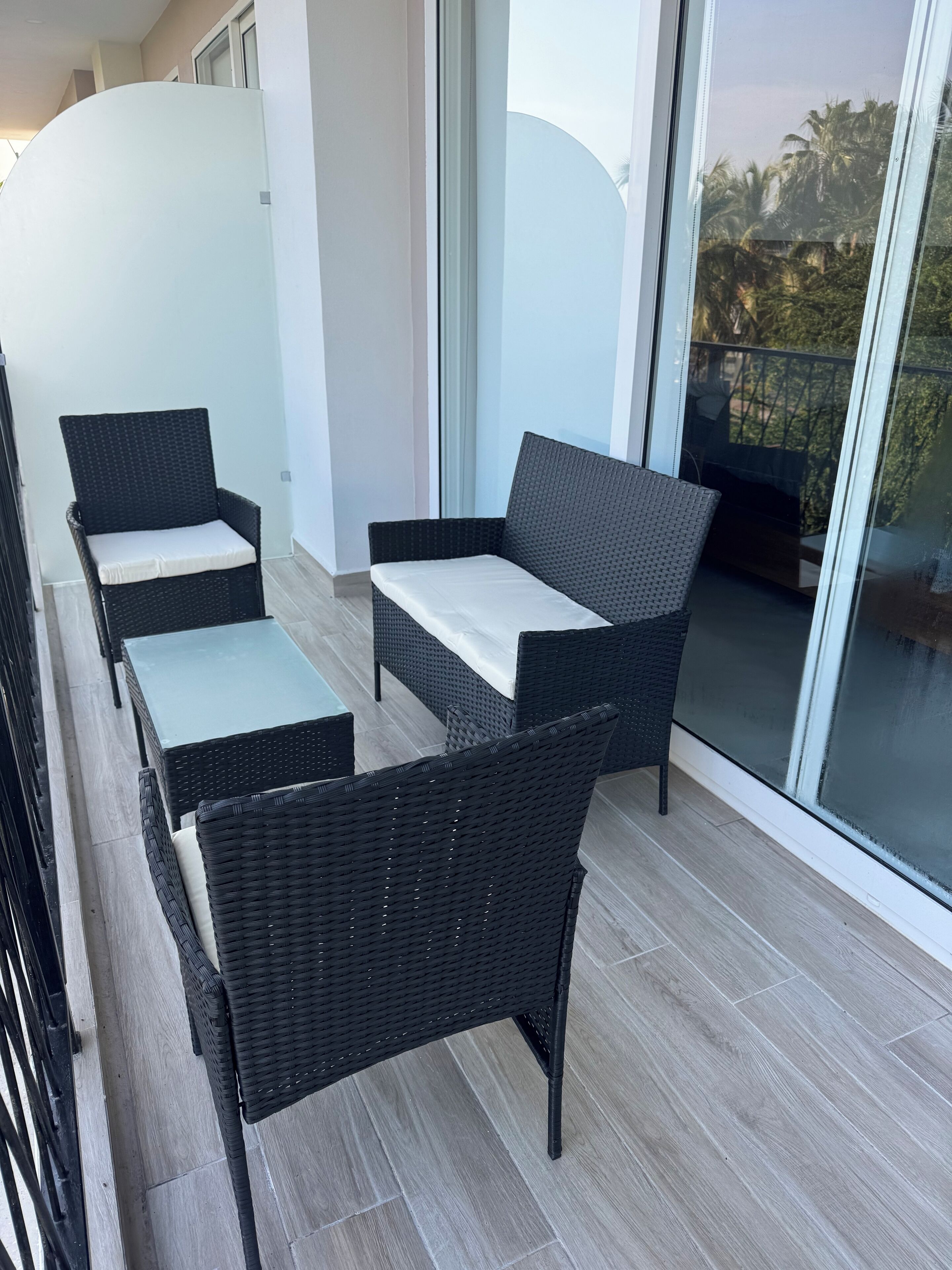 A balcony with wicker furniture, including two chairs and a small table.