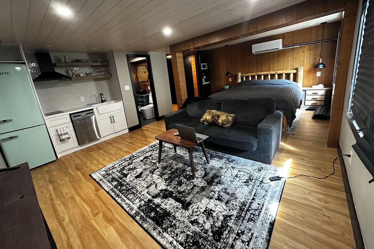 A compact living space with a kitchenette, a sofa, a coffee table, and a bed.